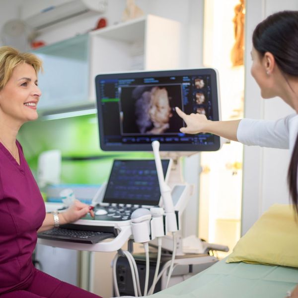 Excited mother points at ultrasound with happy sonographer