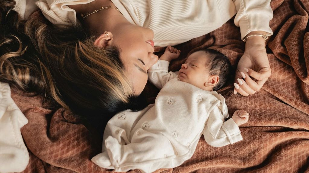 smiling mom lying with her newborn baby