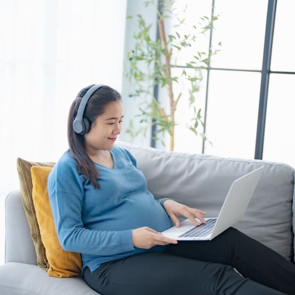 pregnant woman using headphones to listen to baby's heartbeat