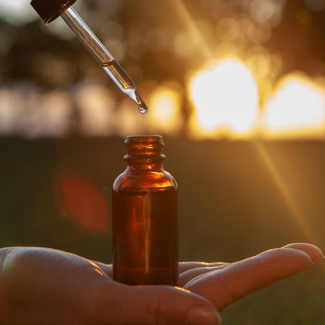 a person holding a bottle of peptide serum in front of a sunset