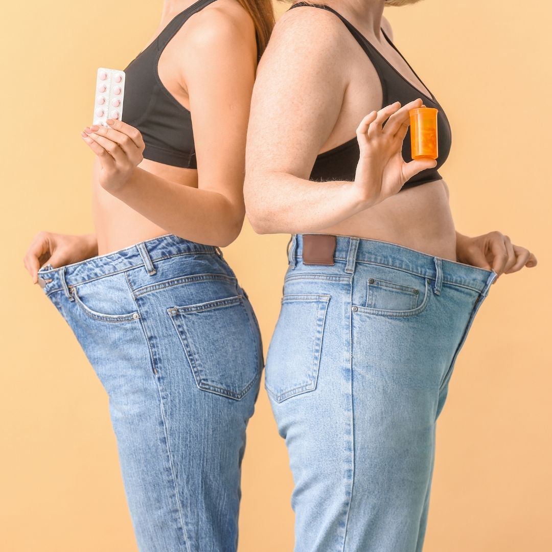 two individuals standing next to each other, one holding an orange and the other holding a pill