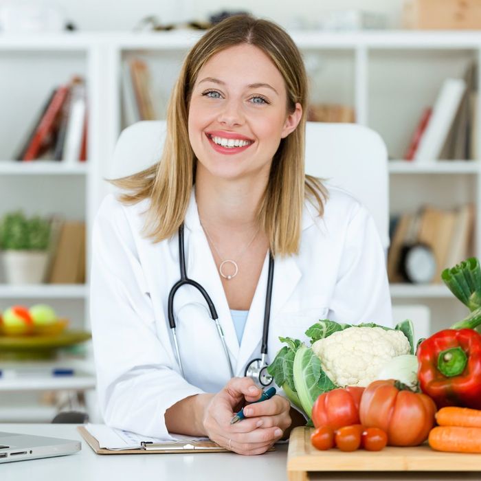 A nutritionist woman smiles in front of veggies