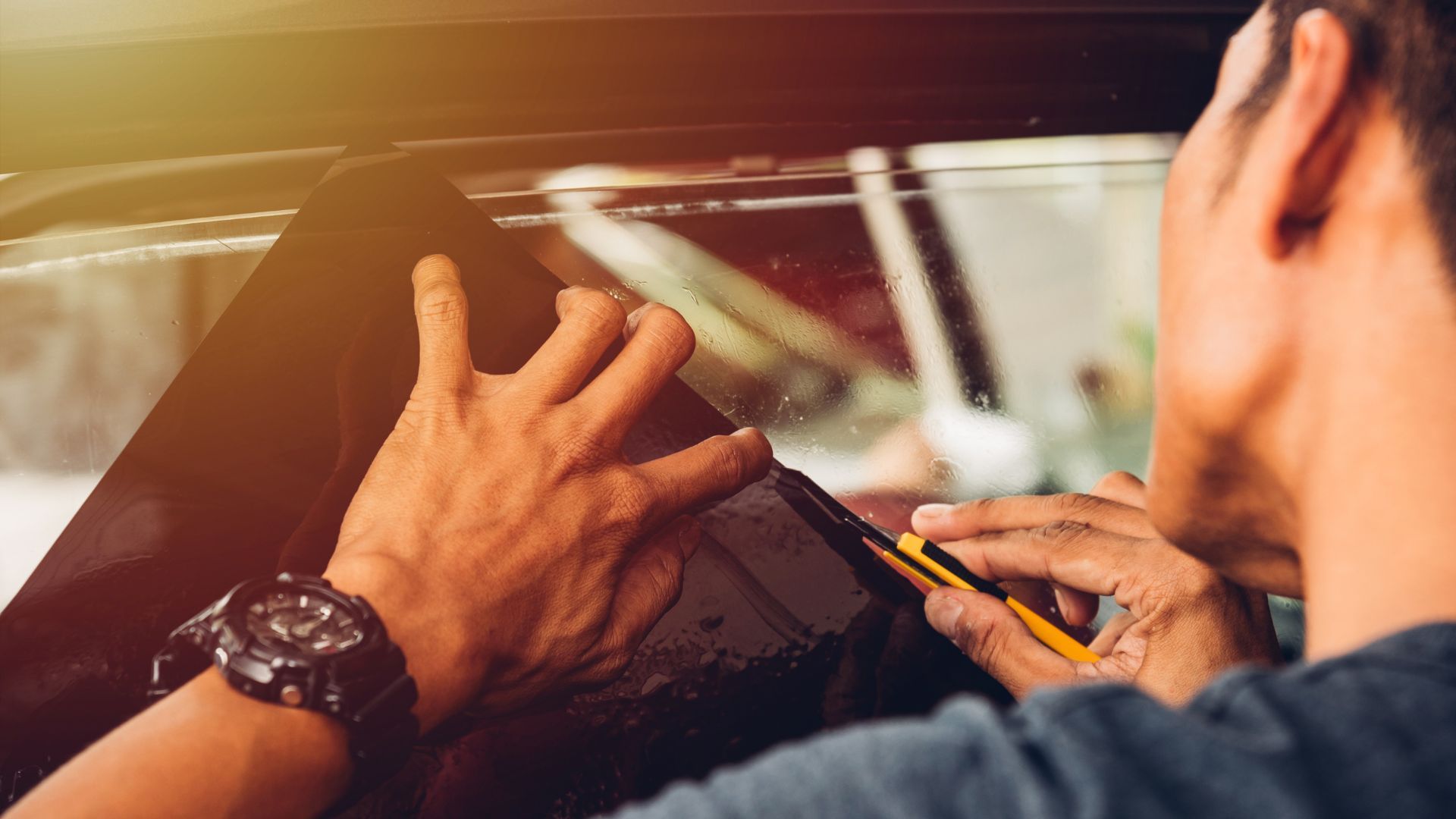 Man applying window tint to a new vehicle.