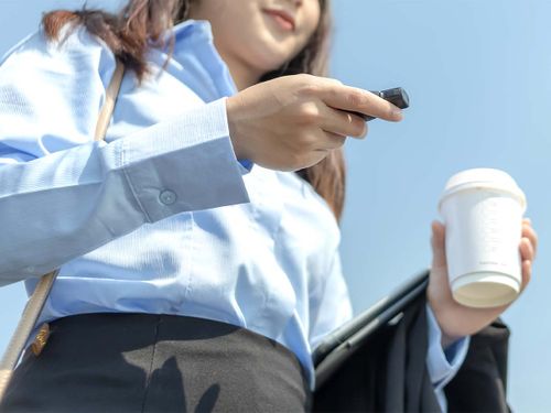 A woman holding coffee and using remote start outside