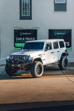 White Jeep Wrangler parked outside Tricked Out Car and Truck Sales with dark SolarFX full ceramic window tint.