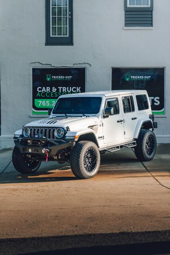 White Jeep Wrangler parked outside Tricked Out Car and Truck Sales with dark SolarFX full ceramic window tint.