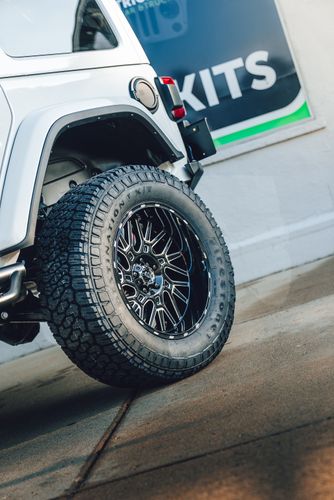 Gloss black Vision aftermarket wheel wrapped in a Firestone Destination X/T off-road tire.