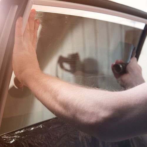 Person applying window tint to a vehicle window. 