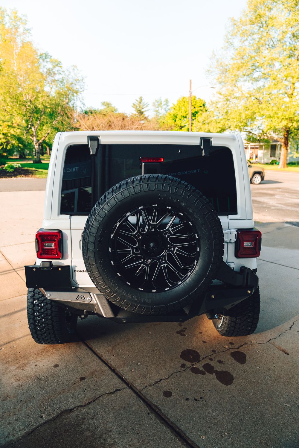 Rear view of Jeep Wrangler showing heavy duty tire carrier holding an oversized off-road spare tire.