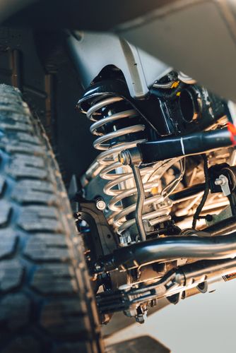 Close up of Rough Country suspension heavy duty coil spring and track bar installed on a Jeep.
