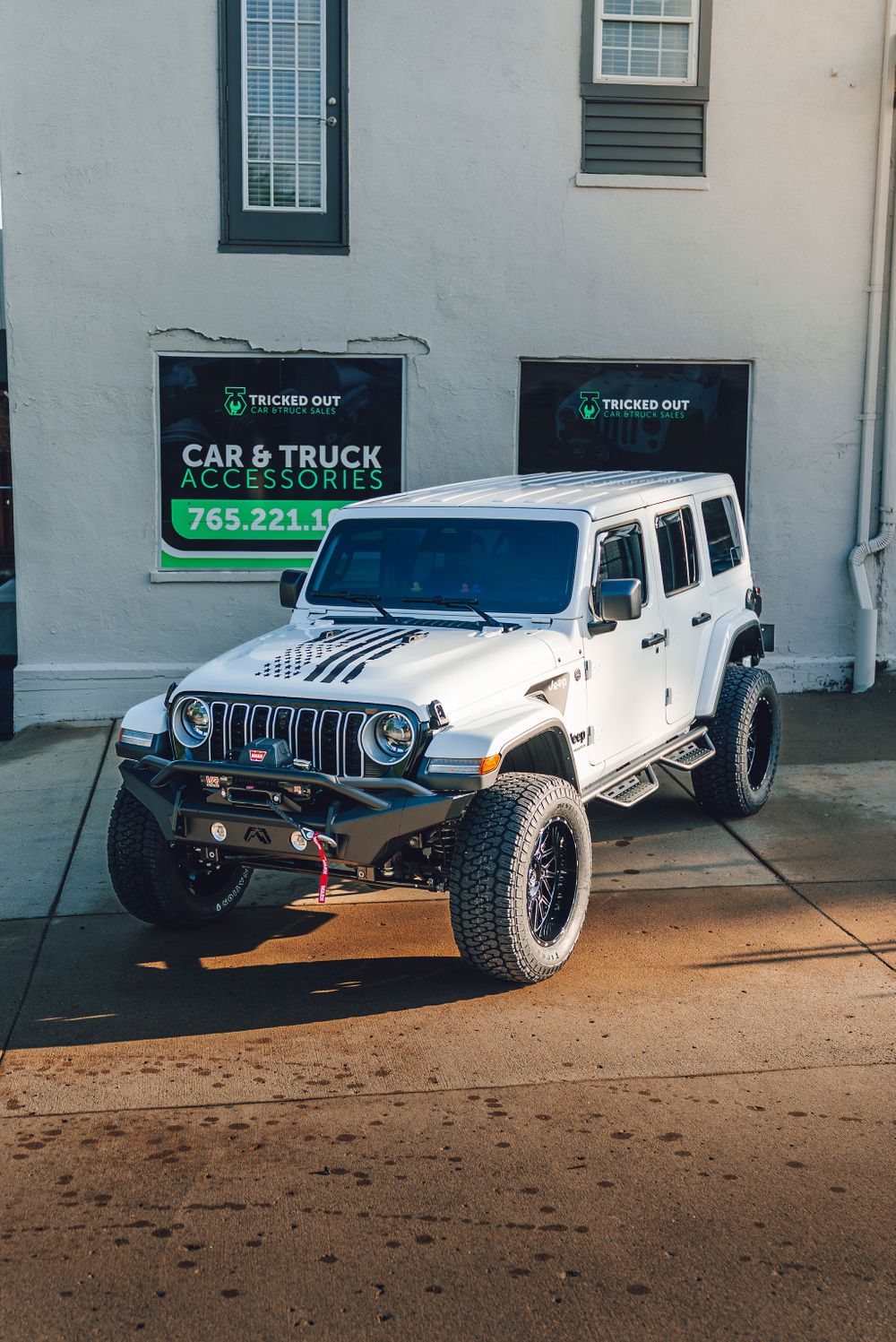 White Jeep Wrangler with custom distressed American flag hood graphic and black wrapped front grille.