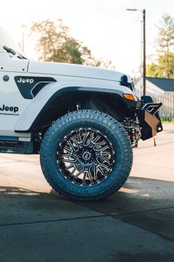 Jeep Wrangler front wheel well exposing Rough Country suspension lift components.