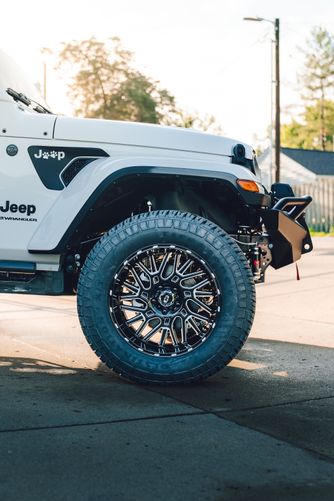 Jeep Wrangler front wheel well exposing Rough Country suspension lift components.