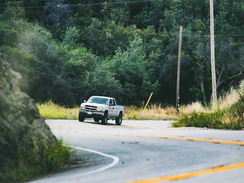 A truck driving around a curvy road through woods