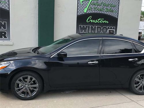 A black car parked in front of Tricked Out Car and Truck Sales