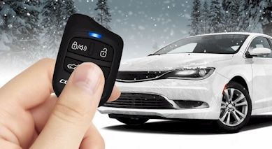 hand holding remote start button and vehicle in snowy background