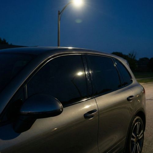 Luxury SUV with dark privacy window tint parked under a streetlamp at night