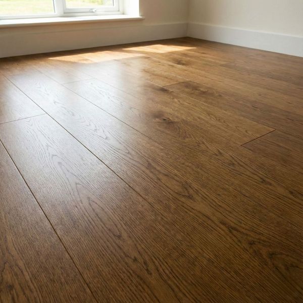High-quality photograph of a newly installed oak hardwood floor, showing the natural wood grain and a smooth satin finish under natural light from a window.