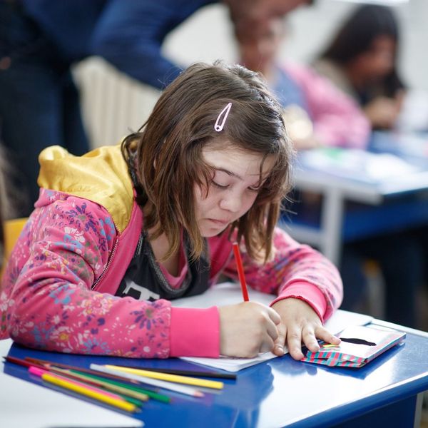 young girl in pick jacket coloring with colored pencils