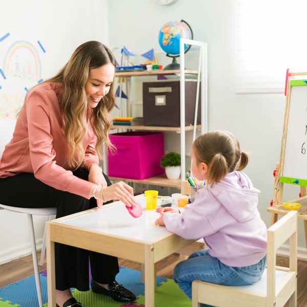 woman playing with young girl at kids table