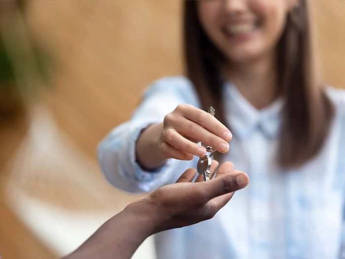 A smiling woman handing house keys to a new owner