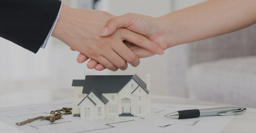 An image of two people shaking hands over a house.