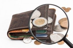 magnifying glass over a wallet with change