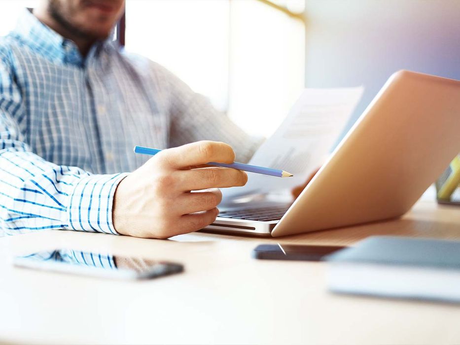 A man at a desk with a laptop and title service documents