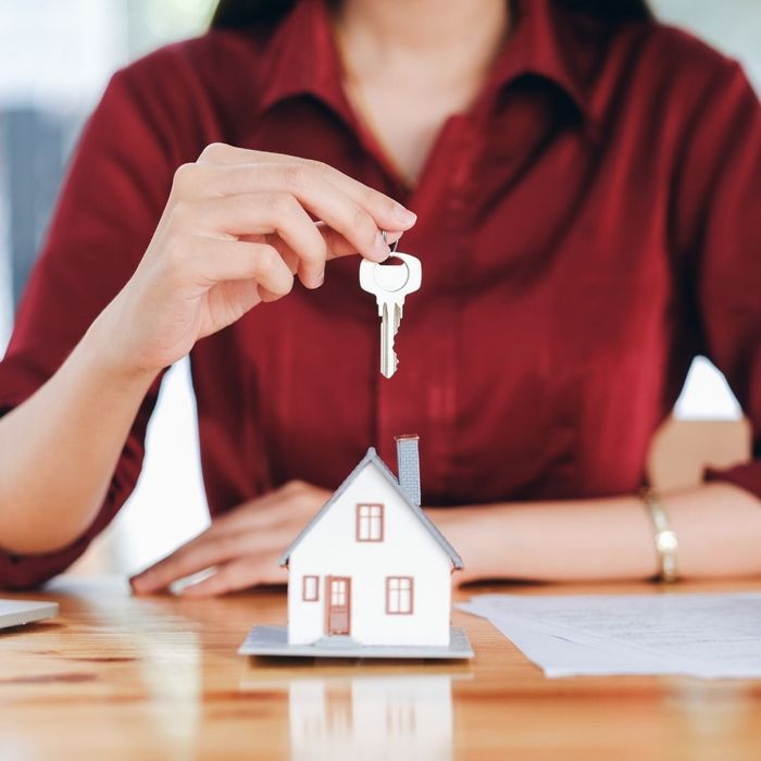 An image of a woman holding a key above a tiny house.