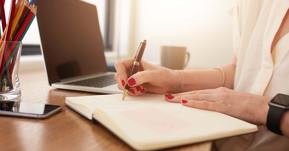 A woman writing in a notebook on her desk at Speedy Title & Escrow Company