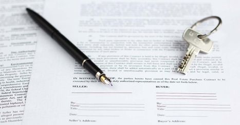 A pen and key sitting on top of a real estate document