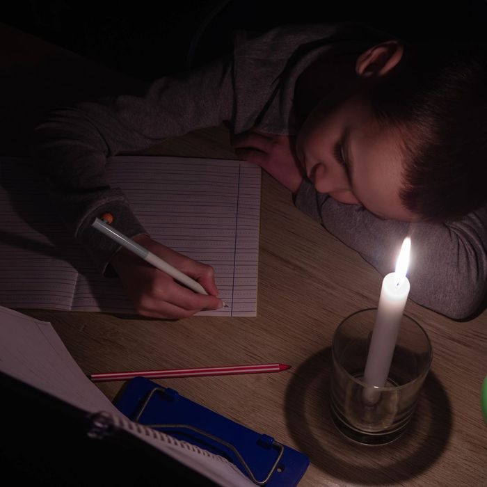 child doing homework by candlelight 