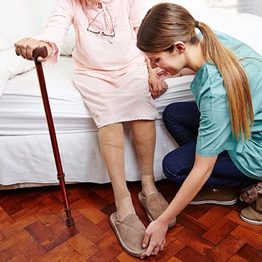 Home Care Worker Helping Elderly Woman With Shoe Image
