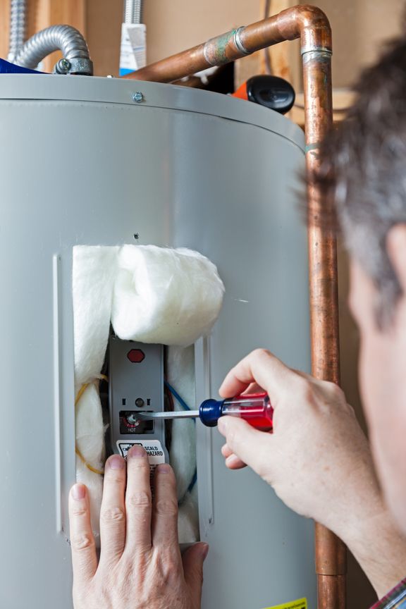 A technician is performing maintenance on a residential water heater.