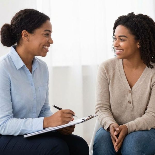 A professional consultant smiling while reviewing a patient's health history intake form on a clipboard.