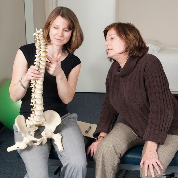 Chiropractor and middle aged woman discuss spinal pain