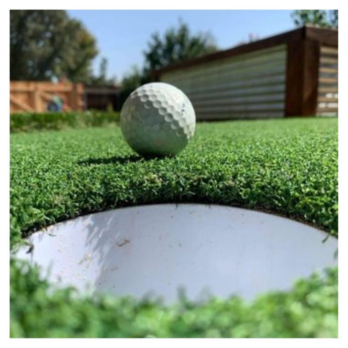 golf ball rolling towards hole in turf