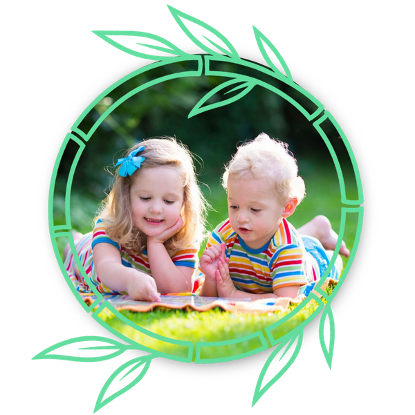 toddlers sitting outside on grass looking at book