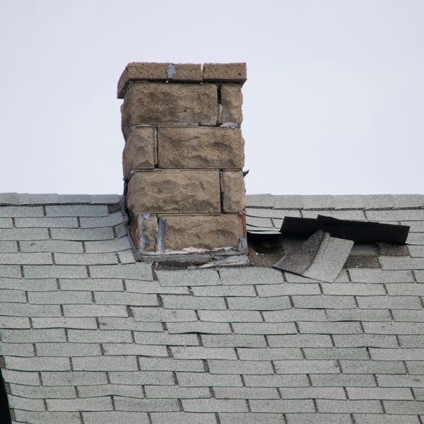 damaged shingles on roof near chimney