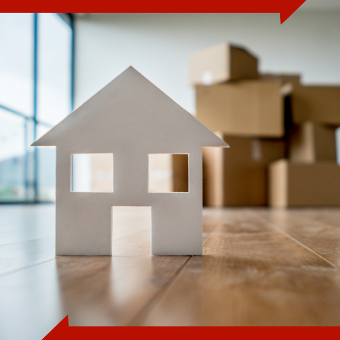 small paper home on floor with boxes in the background