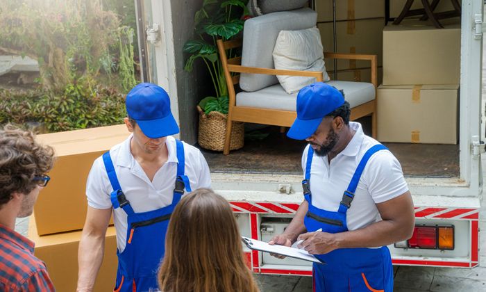 movers with a clipboard talking to a couple