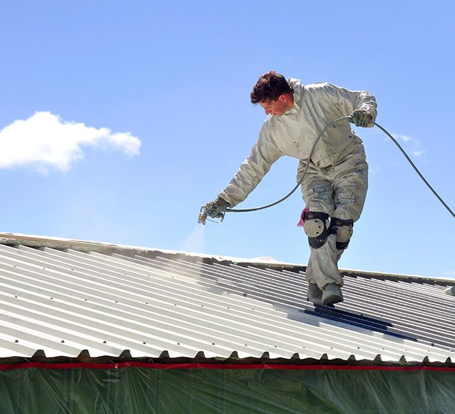 a professional painting a business roof with a spray paint nozzle