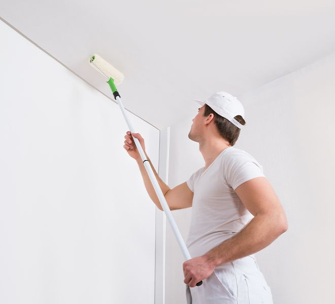 a professional painting a ceiling with a roller