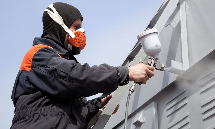 a professional painter using safety gear while painting an exterior