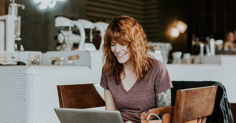 A small business owner smiling while looking at her computer