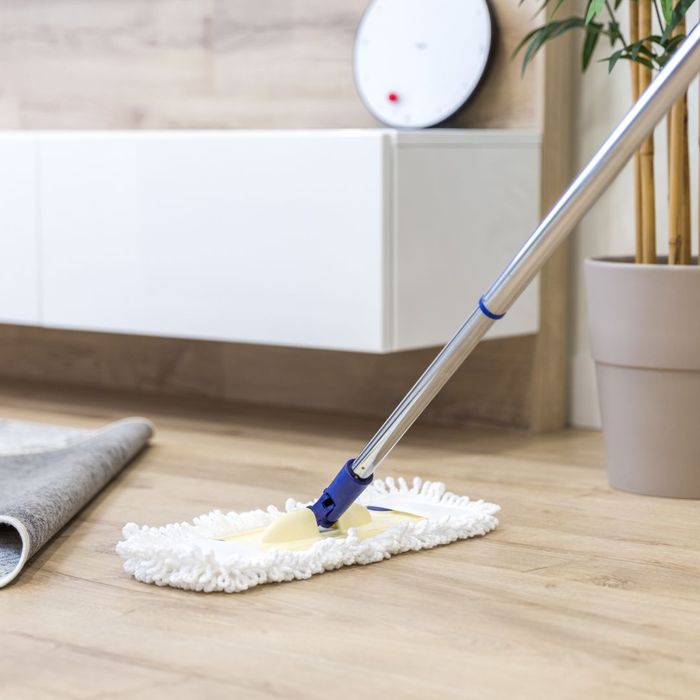 sweeping under rug on wooden floor