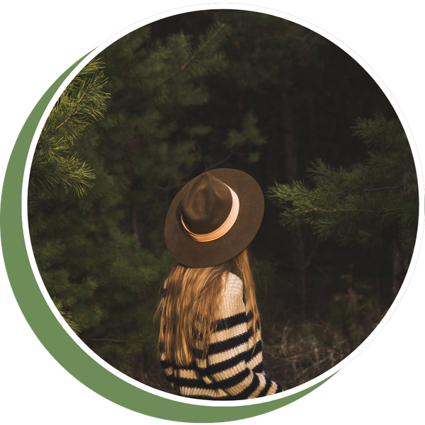 back of a woman with a hat on in a forest