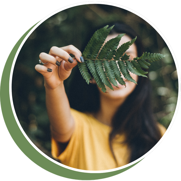 woman holding leaf out in front of face