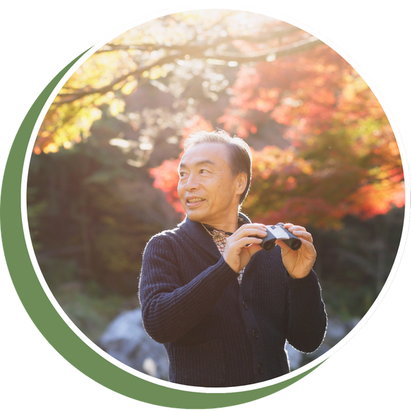 older man standing outside with binoculars