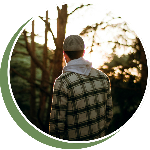 back of a man wearing a beanie standing in forest
